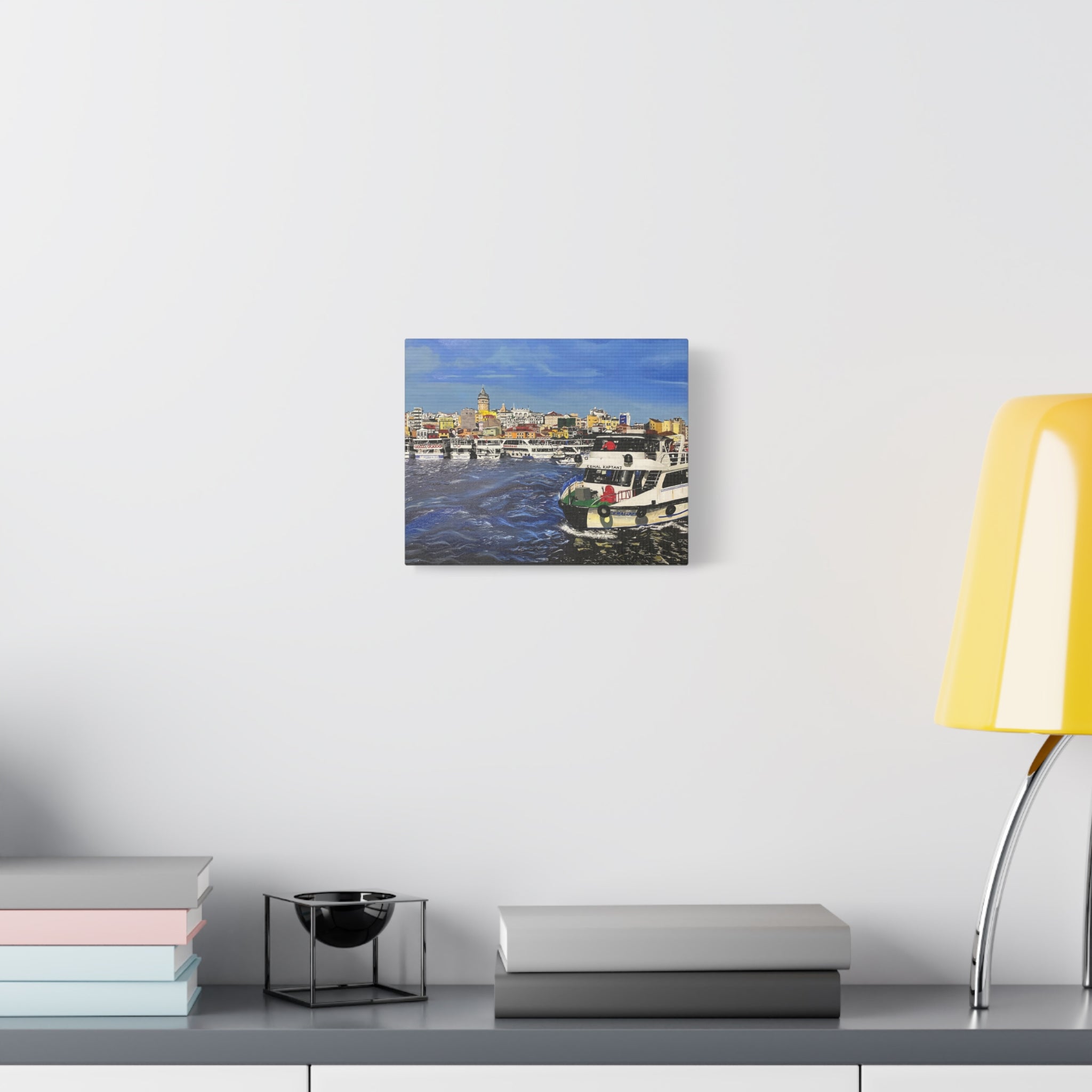 Canvas print of a harbor scene with boats on a white wall above a desk.