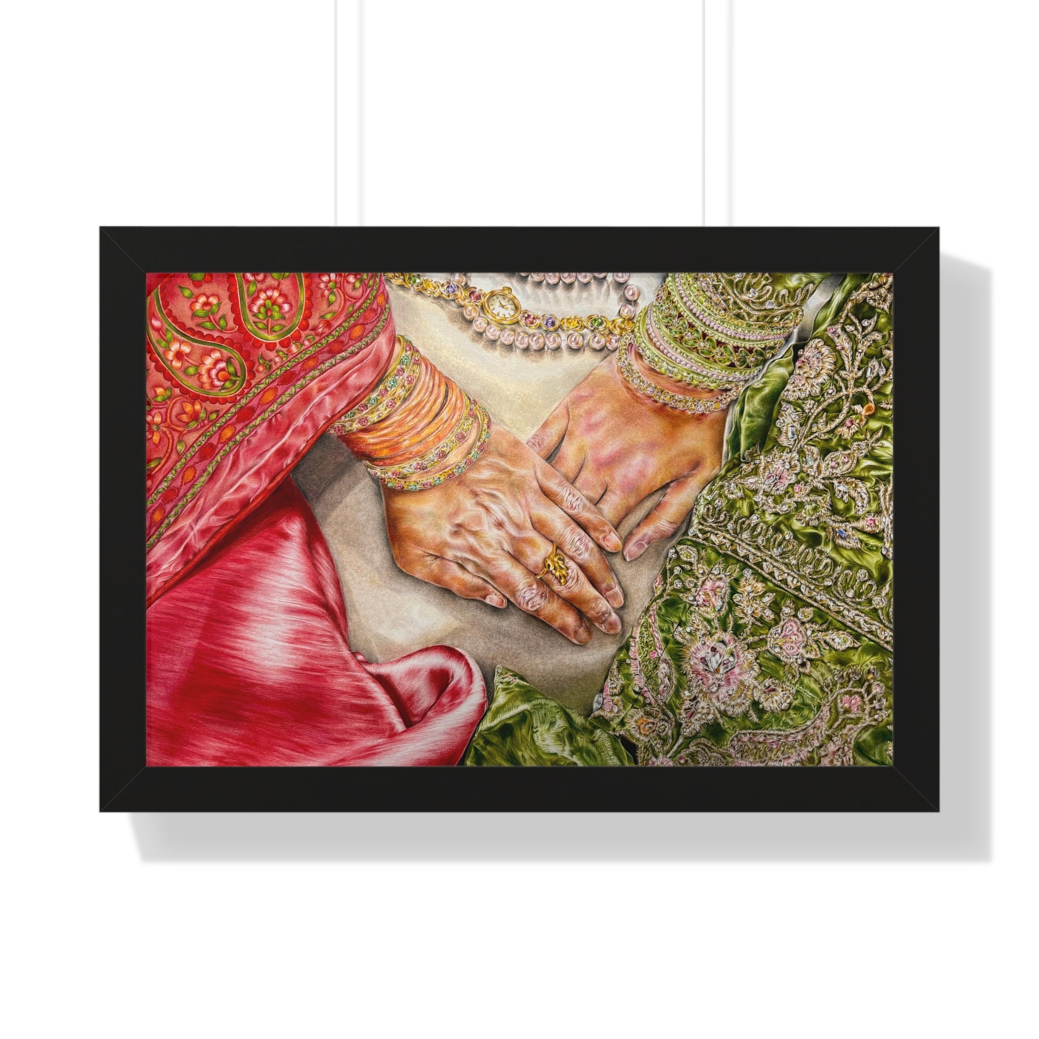 Framed artwork of two hands held together, wearing jewelry, against a white background