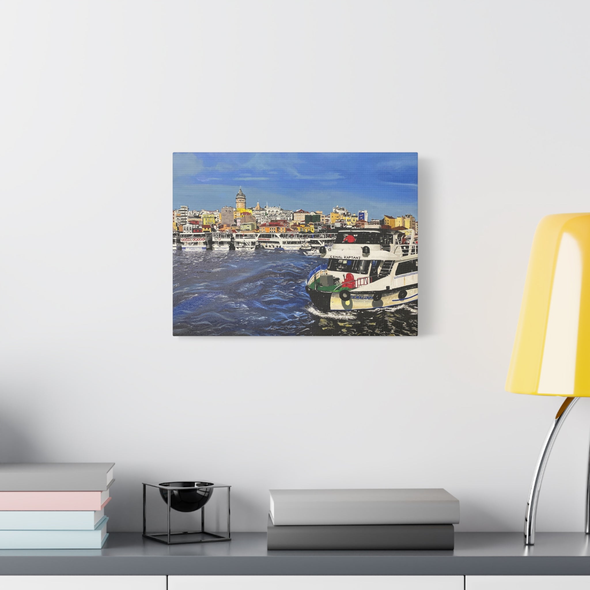 Framed artwork of a cityscape with boats on a wall above a shelf.